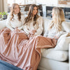 Three sisters sit under a Luxury Extra Large Oversized Throw Rosy (dusty peach) Colored Lush Saranoni Blanket. The soft blanket is an extra large throw blanket and has a soft faux fur feeling.