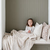 A little girl holds a Toddler Buttermilk (light tan) Colored Lush Luxury Saranoni Blanket. The soft blanket is a small blanket and a baby blanket or toddler blanket.