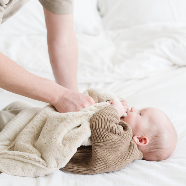 A baby boy holds a Mini Buttermilk (light tan) Colored Lush Saranoni Blanket. The soft blanket is a small blanket and a baby blanket or toddler blanket.