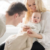 A mother and father smile at their baby boy who is in a Luxury Receiving Buttermilk (light tan) Colored Lush Saranoni Blanket. The soft blanket is a small blanket and a baby blanket or toddler blanket.