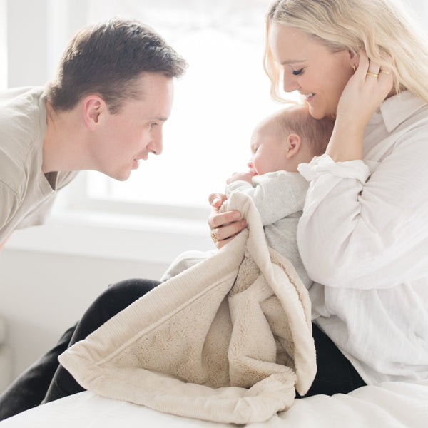 A baby boy holds a Mini Buttermilk (light tan) Colored Lush Saranoni Blanket. The soft blanket is a small blanket and a baby blanket or toddler blanket.