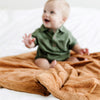 A baby boy sits on a Luxury Receiving Camel (light yellowish brown) Colored Lush Saranoni Blanket. The soft blanket is a small blanket and a baby blanket or toddler blanket.