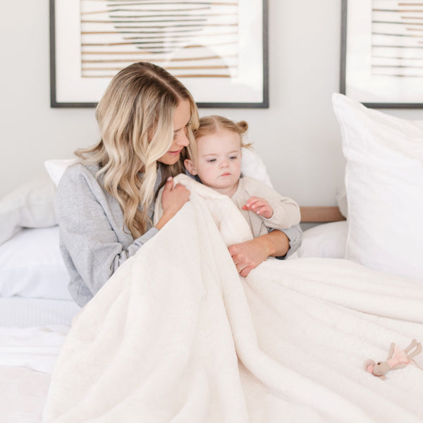 A mother wraps her daughter in a Luxury Toddler Natural (off-white) Colored Lush Saranoni Blanket. The soft blanket is a toddler blanket or baby blanket.