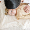 A baby girl lays on a Luxury Receiving Natural (off-white) Colored Lush Saranoni Blanket. The soft blanket is a small blanket and a baby blanket or toddler blanket.