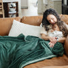 A mother and her daughter sit under a Luxury Extra Large Oversized Throw Hunter Green Colored Lush Saranoni Blanket. The soft blanket is an extra large throw blanket and has a soft faux fur feeling.