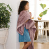 A little girl holds a Toddler Bloom (dusty purple) Colored Lush Luxury Saranoni Blanket. The soft blanket is small blanket and a baby blanket or toddler blanket.