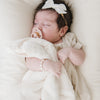 A little baby girls sleeps with a Natural (off-white) Colored Lush Saranoni Blanket draped over her. The soft blanket is a small blanket and a baby blanket.