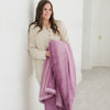 A woman holds a Fairy Wings (light pink/purple) Lush XL Saranoni blanket, designed for oversized comfort and featuring a buttery soft, plush texture. This luxurious Saranoni blanket is perfect for cozy evenings, reading, or home decor. The Saranoni blanket adds warmth, style, and unmatched softness, making it an ideal gift or essential for ultimate relaxation.