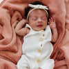 A baby girl lays in a Luxury Receiving Clay Colored Lush Saranoni Blanket. The soft blanket is a small blanket and a baby blanket or toddler blanket.