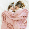 A two little girls who are sisters lay under a Luxury Toddler Ballet Slipper (light pink) Colored Lush Saranoni Blanket. The soft blanket is a toddler blanket or baby blanket.