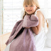 A little girl holds a Toddler Bloom (dusty purple) Colored Lush Luxury Saranoni Blanket. The soft blanket is small blanket and a baby blanket or toddler blanket.