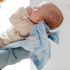 Cute baby cuddled up with a light blue satin border blanket.