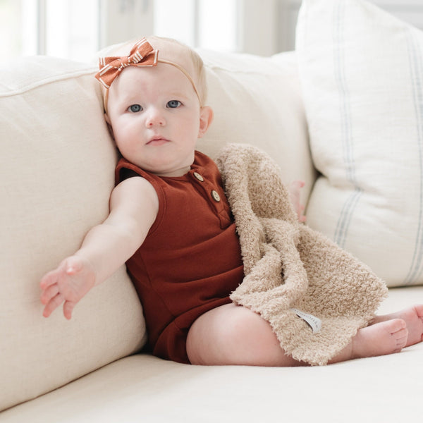 Baby girl sitting on couch with beautiful BAMBONI MINI BLANKETS - Saranoni