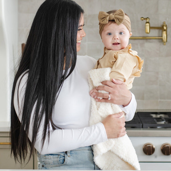 Mom and baby smiling in the kitchen with ivory BAMBONI MINI BLANKETS - Saranoni