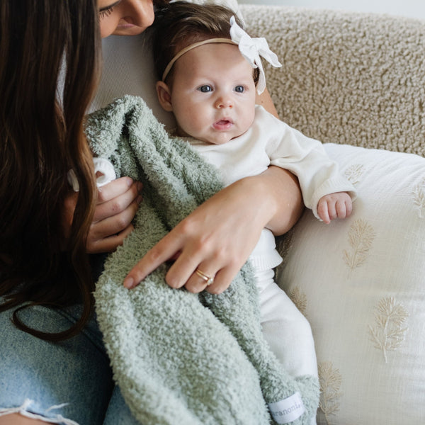 Baby girl snuggling with mom and Sage colored BAMBONI® MINI BLANKETS - Saranoni