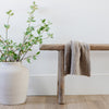 Beautiful home decor including plant, wooden bench, and  neutral colored BAMBONI® MINI BLANKETS - Saranoni