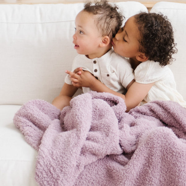 Two kids playing on couch with super soft, purple BAMBONI MINI BLANKETS - Saranoni