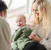 Adorable family with baby boy laughing, wrapped in green BAMBONI MINI BLANKETS - Saranoni