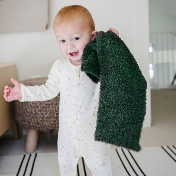 Little boy in pajamas playing with adorable forest green BAMBONI MINI BLANKETS - Saranoni