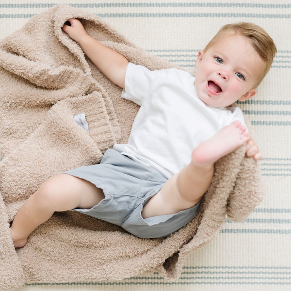 Baby boy playing around on the ground with Birch colored BAMBONI RECEIVING BLANKETS - Saranoni