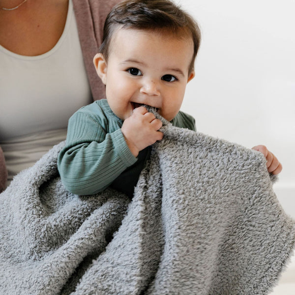 Baby boy playing with super stretchy, soft, gray BAMBONI RECEIVING BLANKETS - Saranoni