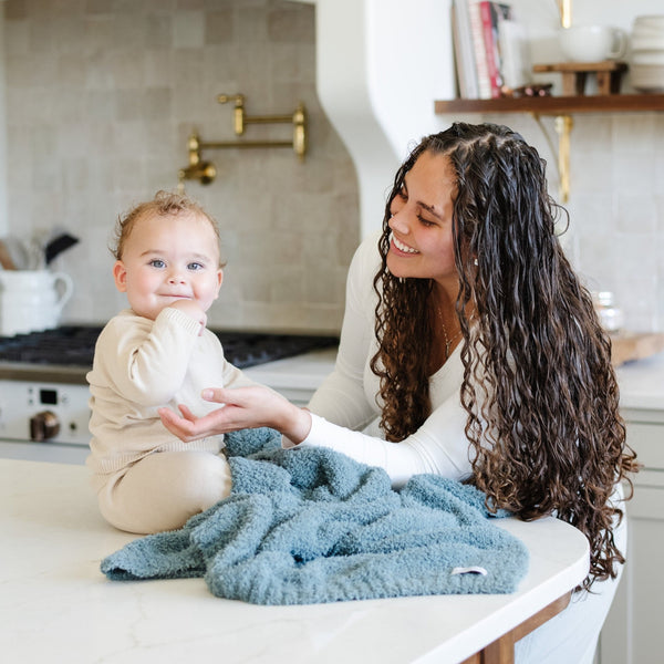 Mom playing with baby boy on counter with Spruce BAMBONI® RECEIVING BLANKETS - Saranoni