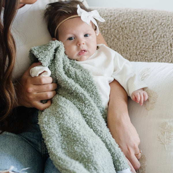 Mom and baby girl sitting on couch with beautiful Sage BAMBONI® RECEIVING BLANKETS - Saranoni