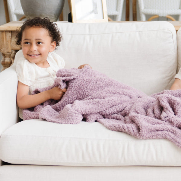 Young girl laying on beautiful white couch with Birchwood BAMBONI RECEIVING BLANKETS - Saranoni