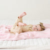 Little girl laying on super soft and stretchy, light pink BAMBONI RECEIVING BLANKETS - Saranoni