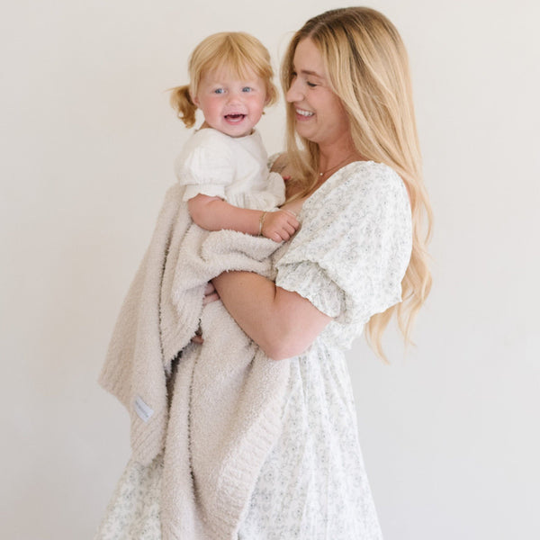 Mom and daughter smiling, wrapped in Buttermilk BAMBONI® RECEIVING BLANKETS - Saranoni