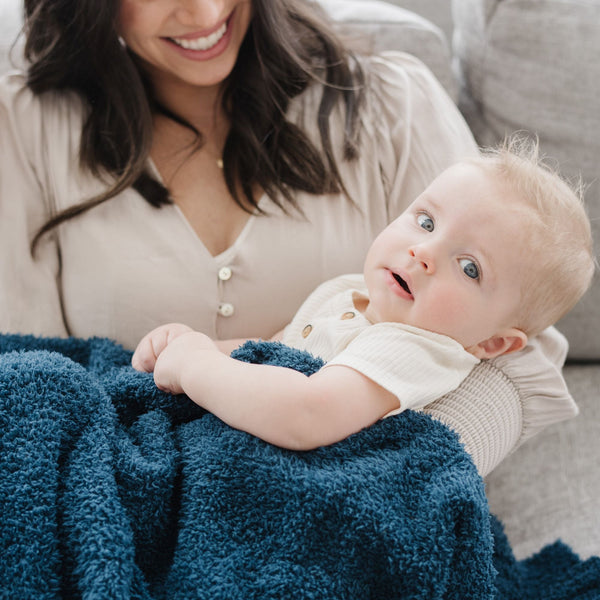 Baby boy with bright blue eyes snuggling with mom, wrapped in Nautical Blue BAMBONI RECEIVING BLANKETS - Saranoni