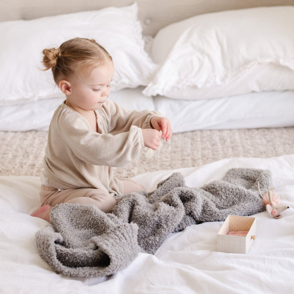 Adorable young girl playing with toys and her favorite gray BAMBONI RECEIVING BLANKETS - Saranoni