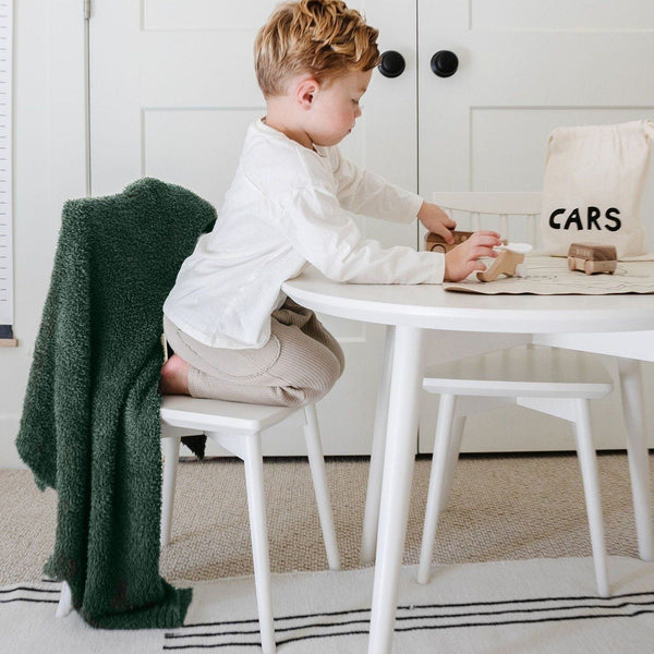 LIttle boy playing at the table with wooden toys, sitting with Juniper BAMBONI RECEIVING BLANKETS - Saranoni