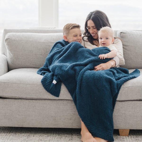 Mom and two kids snuggling on couch with beautiful Nautical Blue BAMBONI THROW BLANKETS - Saranoni