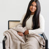 Girl sitting in modern chair with beautiful, stretchy soft Taupe BAMBONI THROW BLANKETS - Saranoni