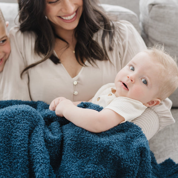 Mom smiling at baby boy wrapped in extra soft and stretchy BAMBONI THROW BLANKETS - Saranoni