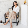 Woman sitting with a good book on a chair with super soft Birch BAMBONI THROW BLANKETS - Saranoni