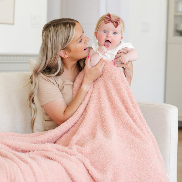 Mom playing with baby girl, snuggled together in Peach BAMBONI® TODDLER BLANKETS - Saranoni