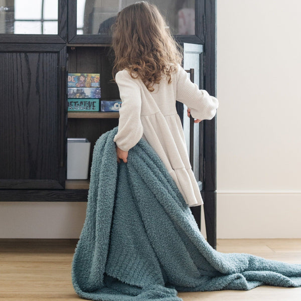 Young girl dragging her favorite Spruce BAMBONI TODDLER BLANKETS - Saranoni