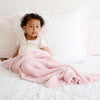 Young girl snuggling in bed with super soft, Light Pink BAMBONI TODDLER BLANKETS - Saranoni