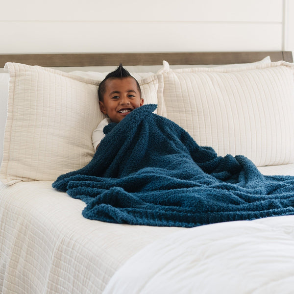 Little boy laying in bed, snuggled in super soft Nautical Blue BAMBONI TODDLER BLANKETS - Saranoni