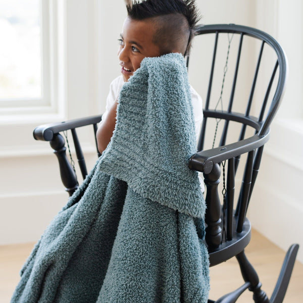 Young boy feeling his super soft and comfy Spruce BAMBONI TODDLER BLANKETS - Saranoni