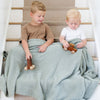 Two young brothers playing with wooden toys with their Sage BAMBONI® TODDLER BLANKETS - Saranoni