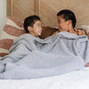 Two little boys sits under a Bamboni® blanket by Saranoni. This ultra-soft blanket is a gray blanket and made from a premium blend of bamboo rayon and poly microfiber, offering a lightweight, breathable, and fluffy feel. Perfect as a toddler blanket, luxury blanket, or soft blanket, it adds warmth and elegance to any bedroom and is a kids blanket. Designed for ultimate comfort, this buttery-soft Saranoni blanket is ideal for gifting. Enjoy this cozy blanket for years to come!