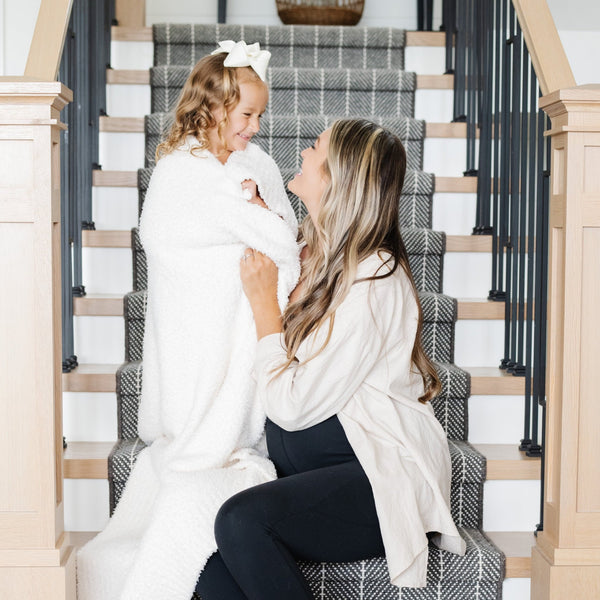 Mom and daughter sitting on stairs, playing with Ivory BAMBONI® TODDLER BLANKETS - Saranoni