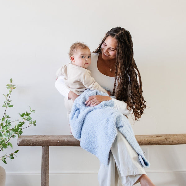 Mom and baby boy sitting on wooden bench, wrapped in Light Blue BAMBONI® TODDLER BLANKETS - Saranoni