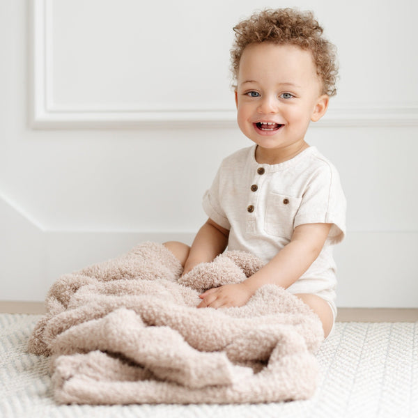 Smiling young boy playing on floor with Birch BAMBONI TODDLER BLANKETS - Saranoni