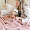 A mother and her little girl sit under a Bamboni® blanket by Saranoni. This ultra-soft blanket is a clay colored blanket and made from a premium blend of bamboo rayon and poly microfiber, offering a lightweight, breathable, and fluffy feel. Perfect as a toddler blanket, luxury blanket, or soft blanket, it adds warmth and elegance to any bedroom and is a kids blanket. Designed for ultimate comfort, this buttery-soft Saranoni blanket is ideal for gifting. Enjoy this cozy blanket for years to come!