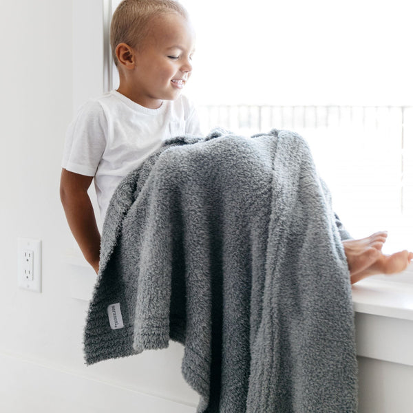 Young boy sitting in window sill, wrapped in gray BAMBONI TODDLER BLANKETS - Saranoni