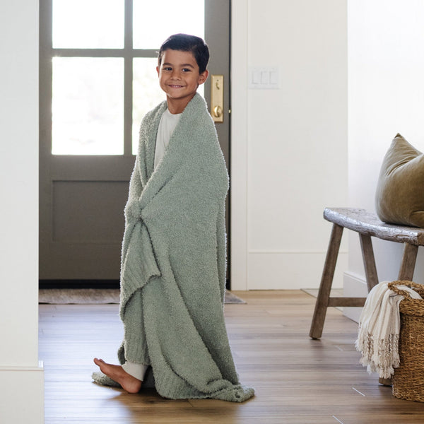 Little boy smiling and walking around beautiful home in his Sage 'BAMBONI® TODDLER BLANKETS - Saranoni